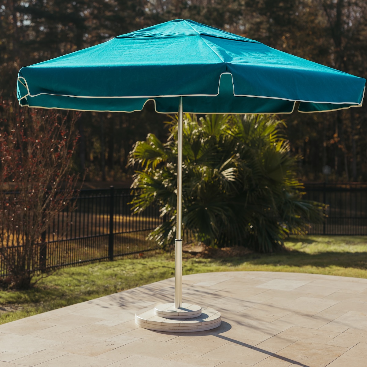Palmetto umbrella and round anchor base paired with coordinating furnishing accessories on patio