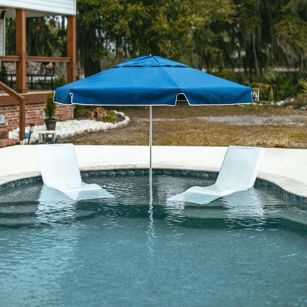 Outdoor umbrella adding shade to a residential pool sun shelf
